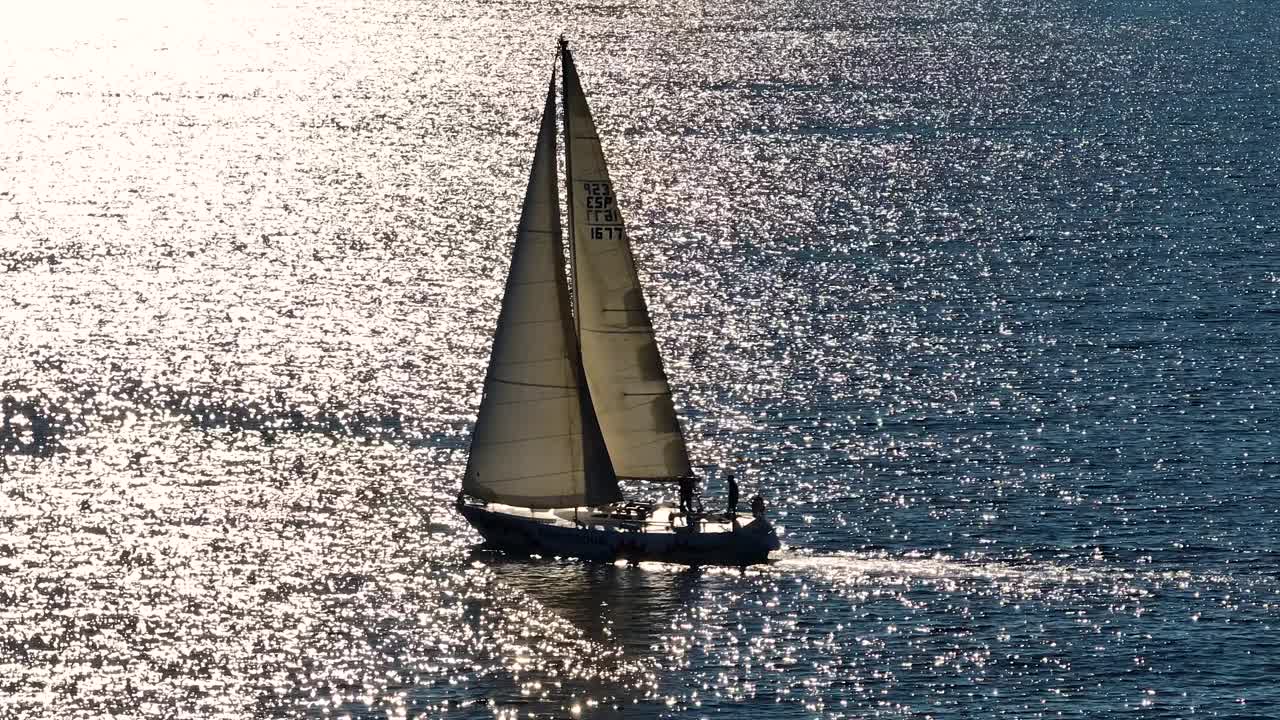 美丽的帆船航行在热带异国情调的海湾与深蓝色的大海。在夕阳的余晖中建立游艇的航拍。无人机拍摄的海上帆船的剪影视频素材