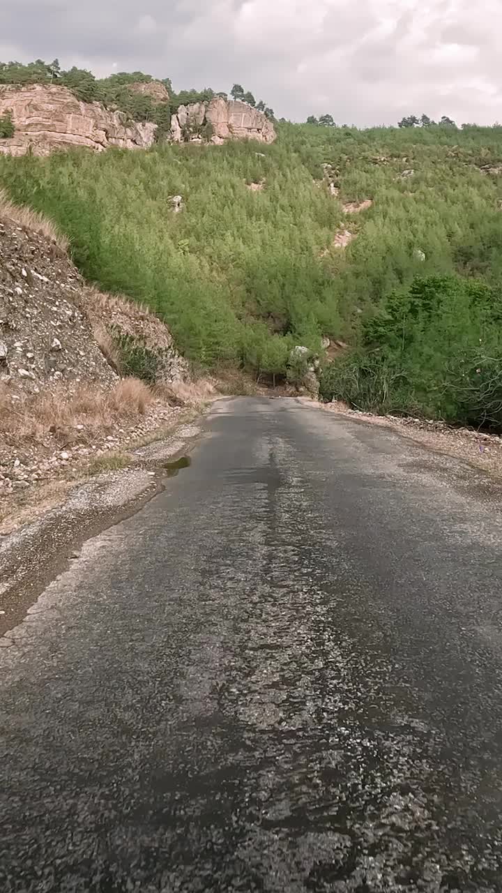 在山路上驾驶，第一人称视角。行程沿着蜿蜒的山路，黑色沥青风景。汽车之旅，蜿蜒山路之旅视频素材