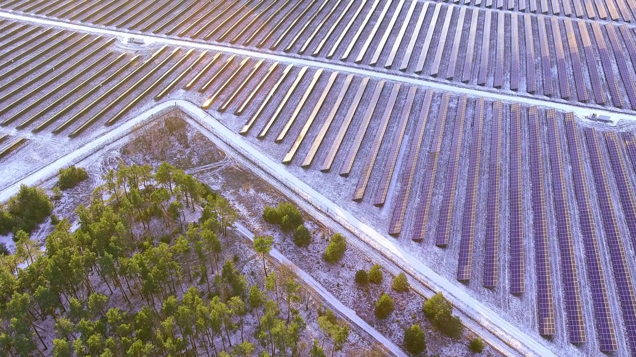 在场地上一排排安装了大量的光伏太阳能电池板，在日落时产生绿色电力。可再生能源生产理念。无人机的鸟瞰图视频下载