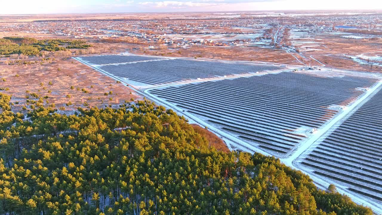 在场地上一排排安装了大量的光伏太阳能电池板，在日落时产生绿色电力。可再生能源生产理念。无人机的鸟瞰图视频下载