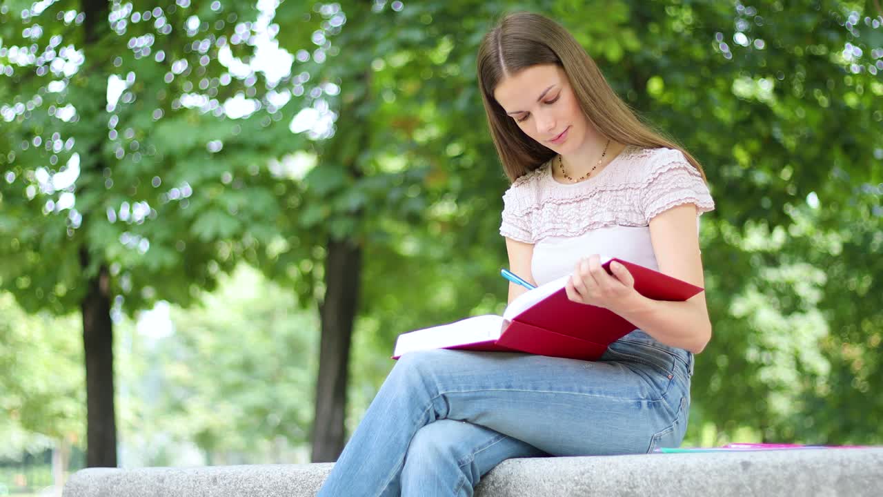 美丽的女大学生在公园的长椅上看书视频下载