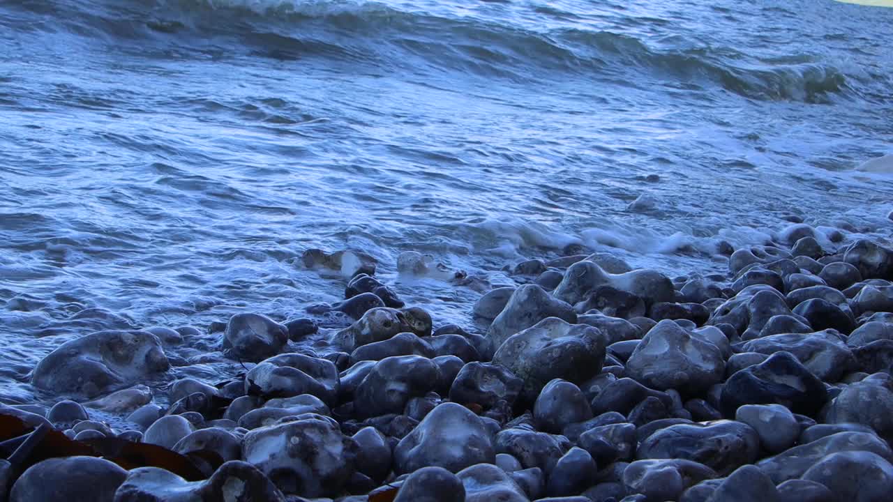 从低角度看，破碎的海浪拍打着海滩上的岩石视频素材