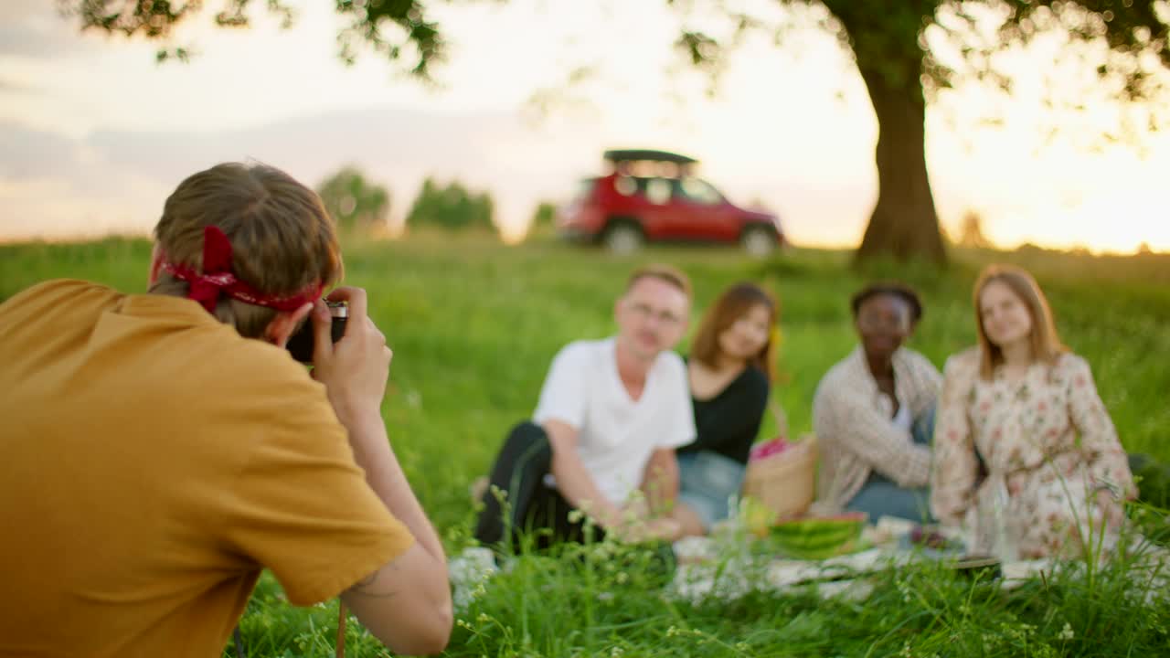 一名男子用模拟相机拍摄夏天户外形形色色的人视频下载