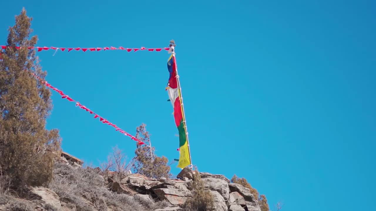 在喜马偕尔邦拉胡尔山谷的沙舒尔寺，冬天，在喜马拉雅雪峰前，经幡在风中飘扬的慢动作镜头。视频素材