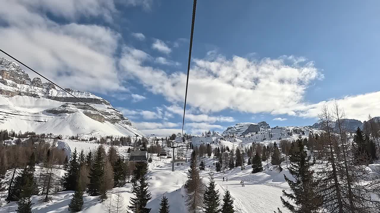 在一个美好的阳光明媚的日子里，滑雪者的缆车正在移动到滑雪道的顶部视频下载