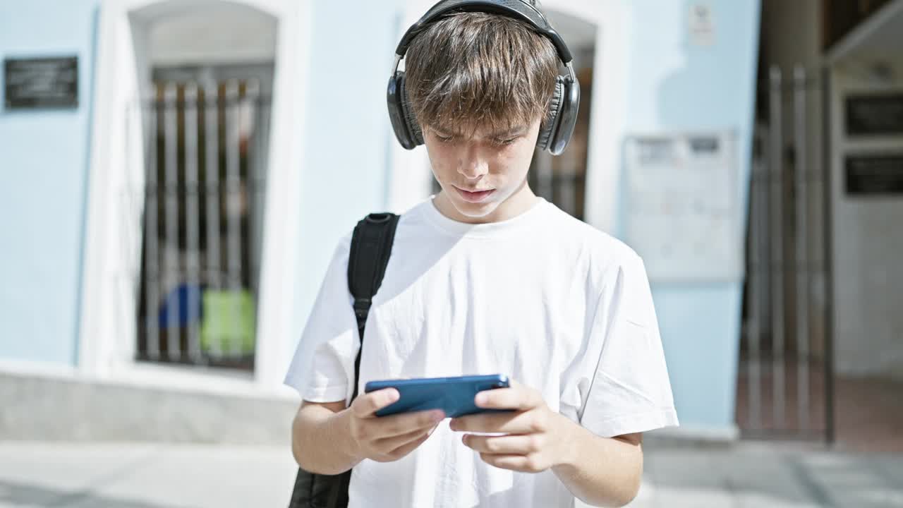 一名年轻的白人男子在城市户外使用智能手机时戴着耳机听音乐。视频素材