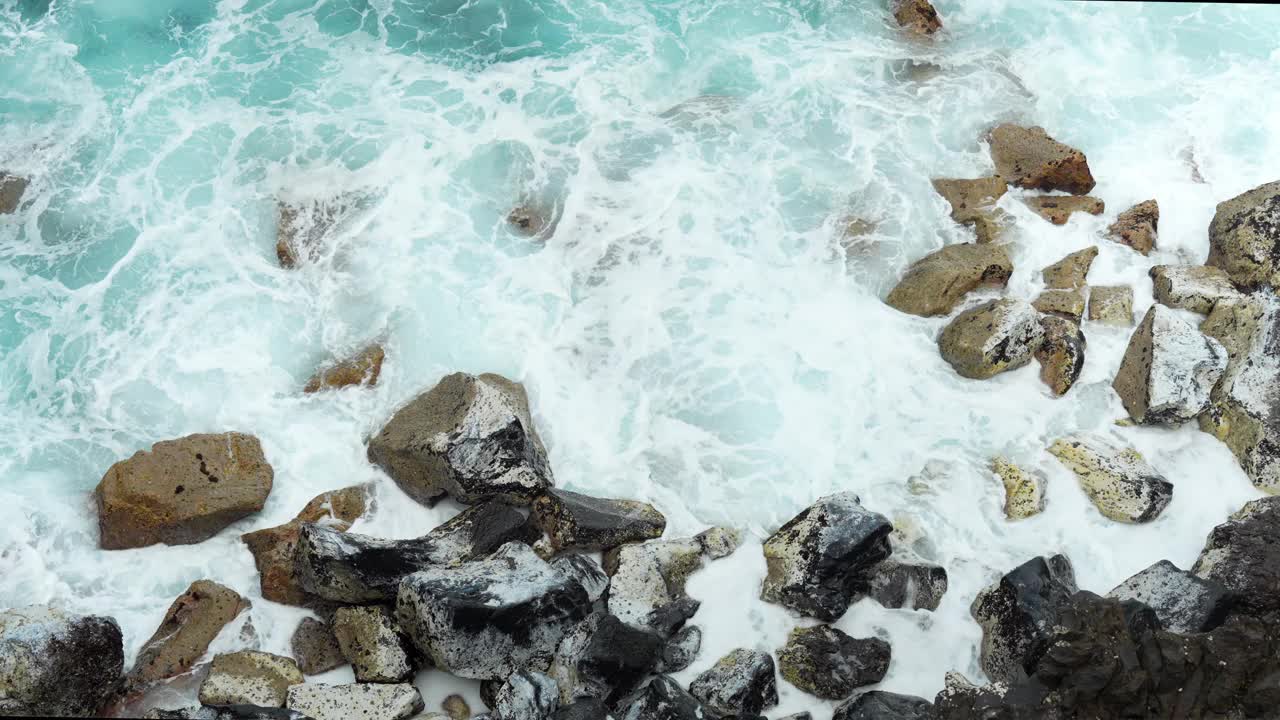 泡沫海浪在特内里费岛海岸附近的岩石上流动，俯视图视频素材