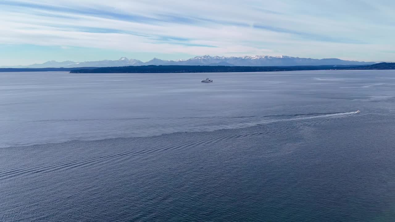 在一个阴天，两艘船航行在风景秀丽的普吉特海湾附近的里士满海滩咸水公园，背景是奥林匹克山脉。视频素材