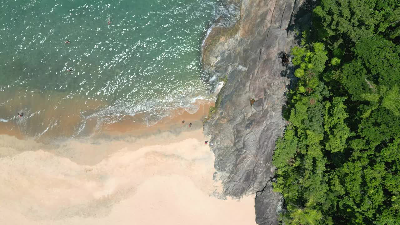 海滩的鸟瞰图，旁边是山。静电，有人在水里。视频下载