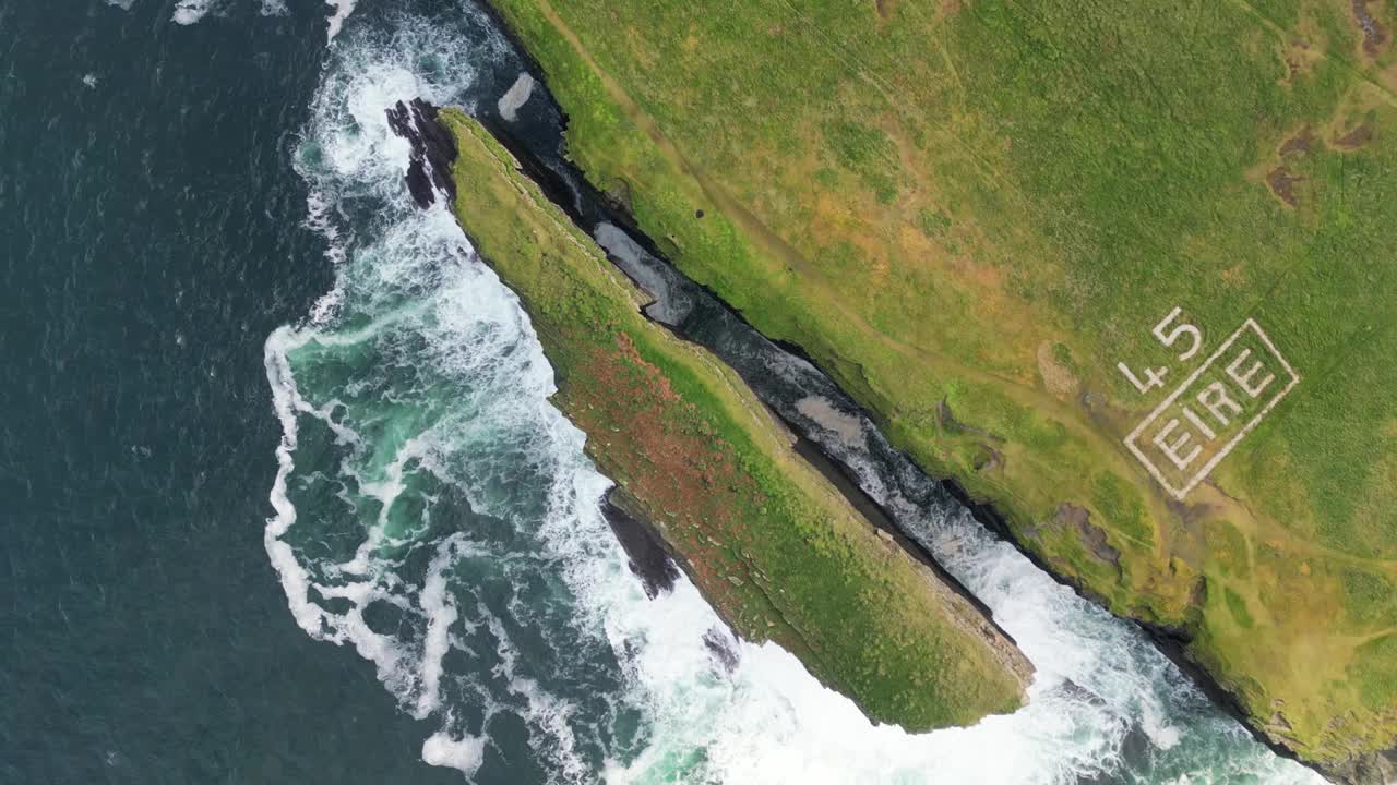 起伏的鸟瞰图，崎岖的海岸线上有“ÉIRE”的标志，海浪冲击着悬崖视频素材