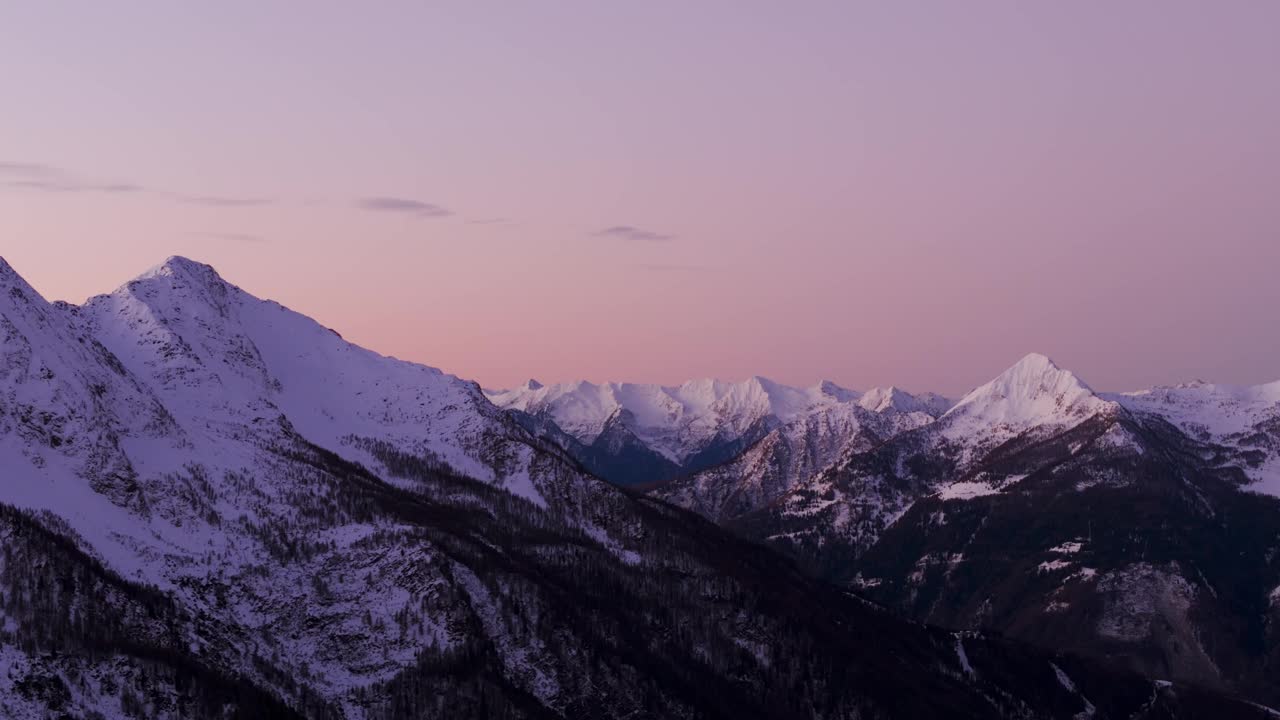 冬日里，白雪覆盖的阿尔卑斯山脉上，落日时粉色的天空。空中无人机视图和复制空间视频素材