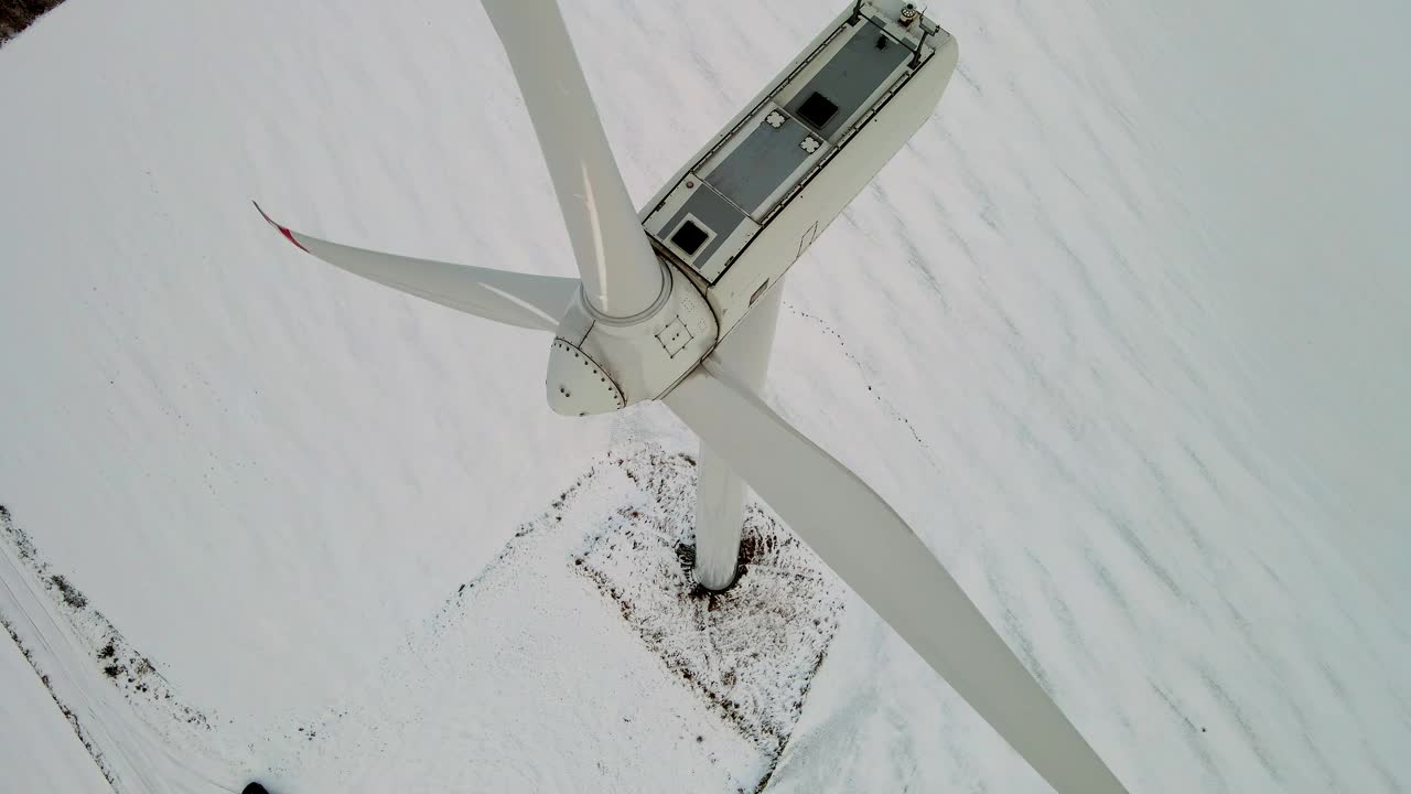 在寒冷的冬季日落与雪中，风车农场风力发电机的旋转叶片产生环境生态能源视频素材