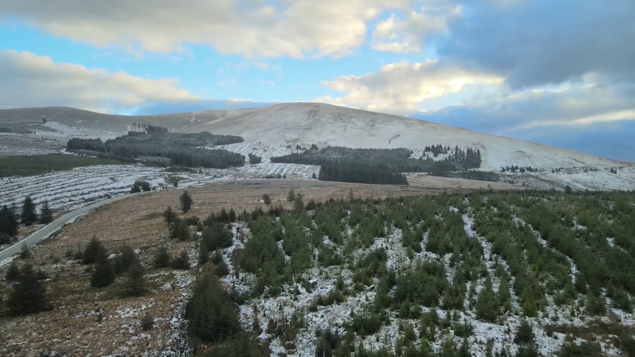 雪山景观与针叶林和清晰的道路，在部分多云的天空下，鸟瞰视频素材