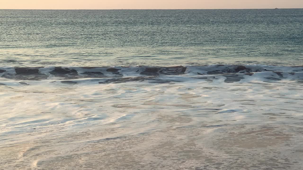 海边海滩的电影时刻，晚上海浪轻轻地拍打着海岸，揭示了广阔的海洋表面。视频素材