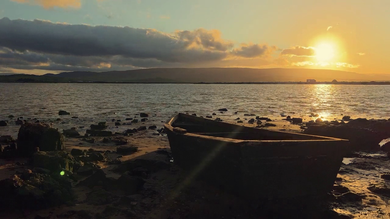 延时拍摄的一艘小船在宁静的河岸上，太阳落在散乱的云后视频素材
