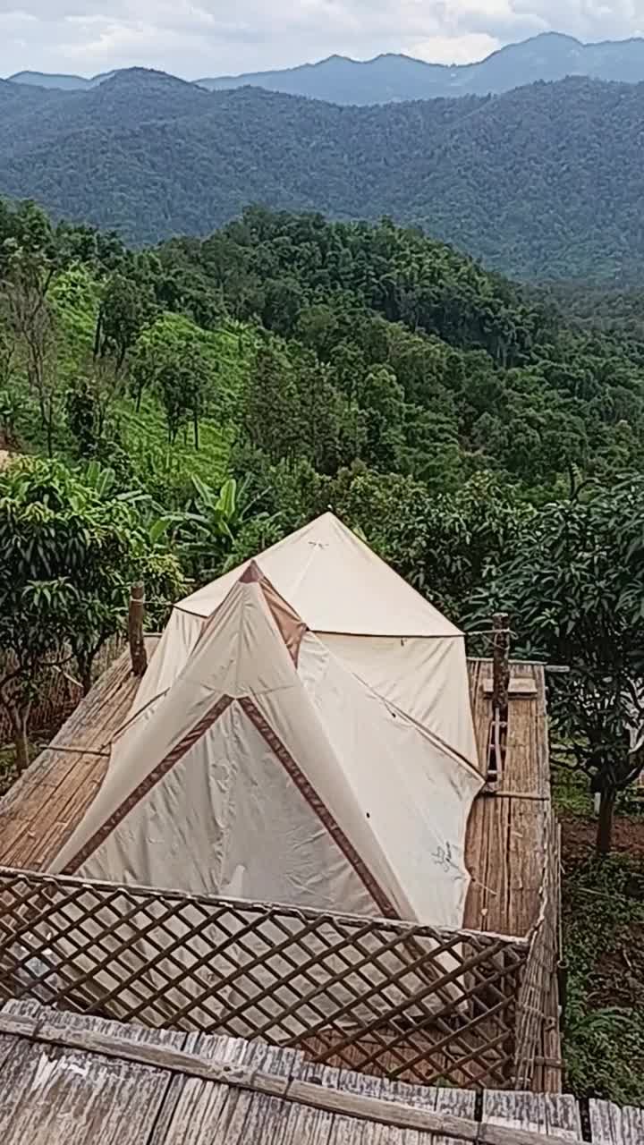 在自然丘陵的山地营地上，白色登山和露营帐篷旅行鸟瞰图视频下载