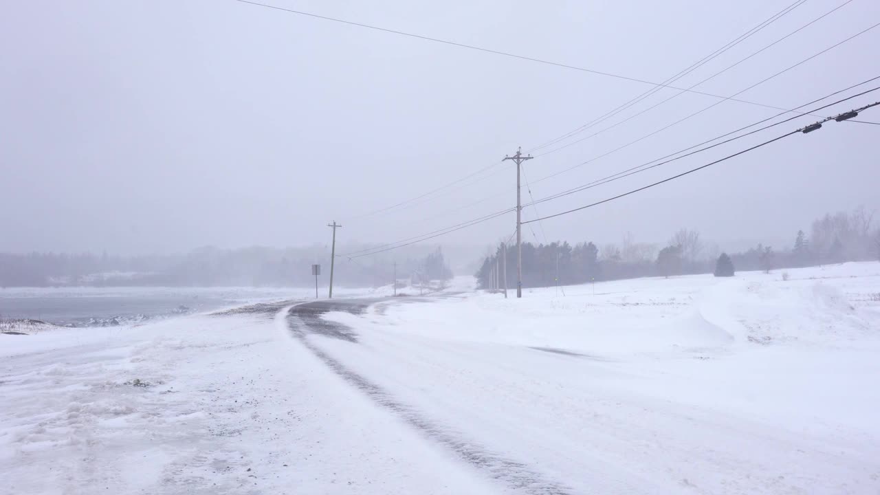 暴风雪中行驶在乡村道路上的汽车。危险的驾驶条件。视频下载