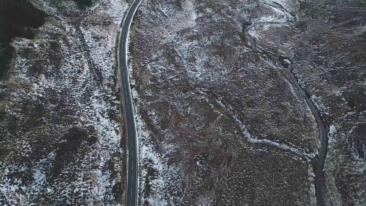 蜿蜒的道路穿过雪景，苏格兰斯凯岛，宁静而孤立，俯视鸟瞰视频素材