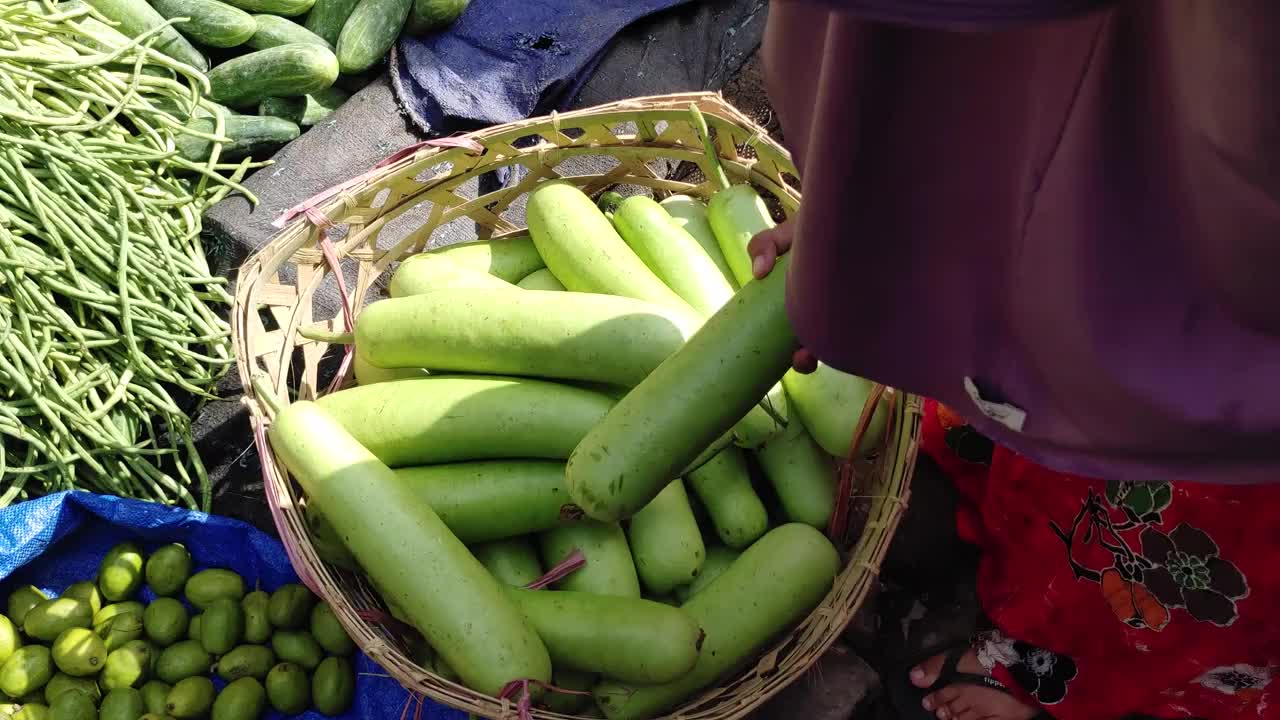 一名印度尼西亚妇女在传统市场挑选绿色茄子水果。在当地市场购物，近距离观看，4k分辨率视频下载