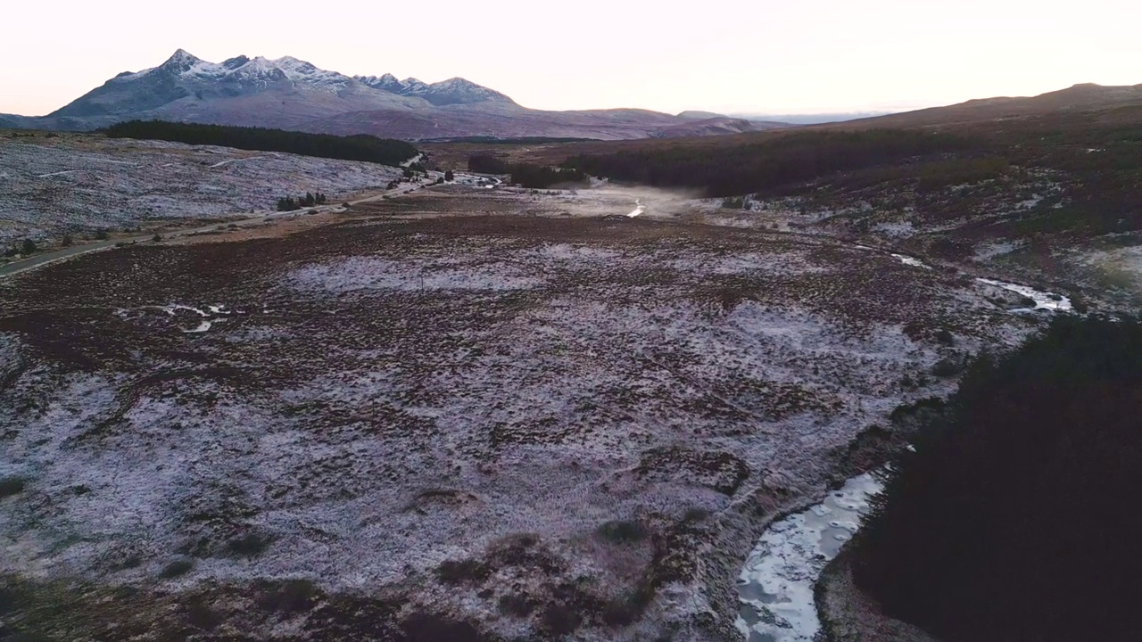 蜿蜒的道路穿过积雪覆盖的景观，黄昏时的山景，鸟瞰图视频素材