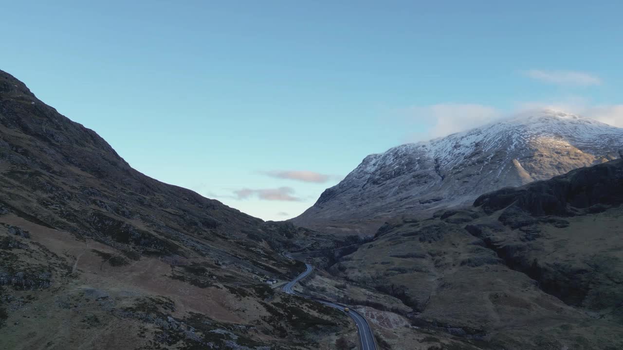 弯弯曲曲的道路穿过白雪皑皑的格伦科山脉，黄昏时分，宁静而雄伟，鸟瞰视频素材