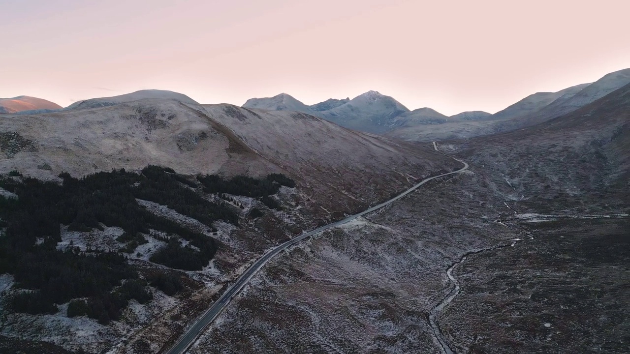 弯弯曲曲的道路穿过黎明的雪景天空，鸟瞰视频素材