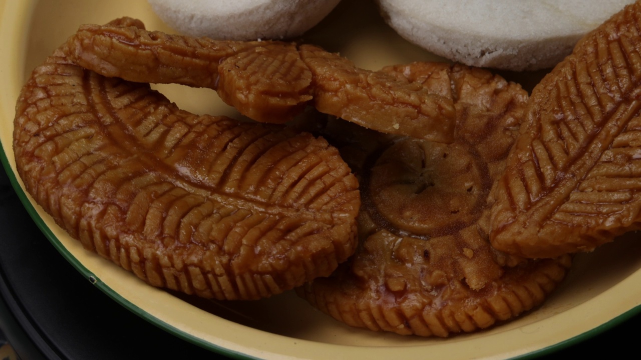 孟加拉甜沙漠装饰的米花糖包nakshi pakkon皮塔饼和蒸巴帕皮塔饼，里面塞满了棕榈糖和椰子片，放在木制背景上的搪瓷锡盘上视频下载