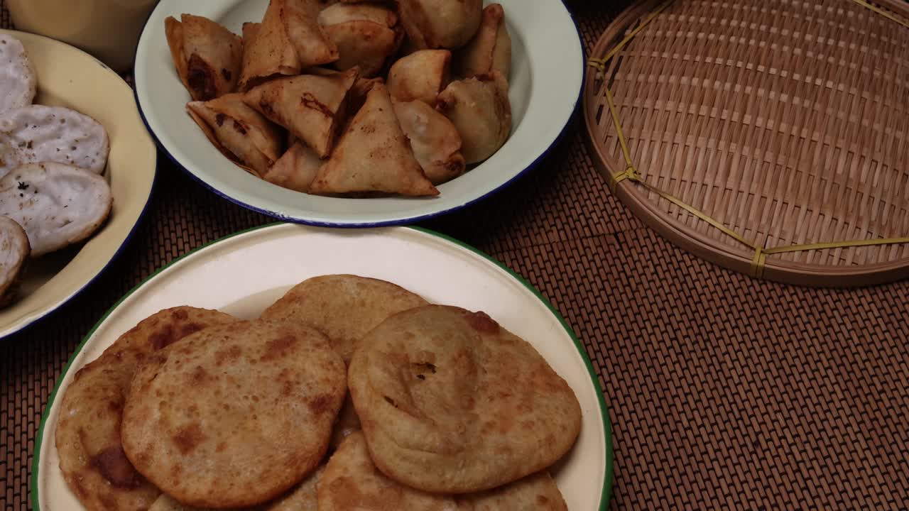 孟加拉风味小吃，各种馅煎饼chitoi bhapa nakshi pakkon pitha singara samosa dal aloo puri炸扁米饭，混合在搪瓷锡金属板上，背景质朴视频下载