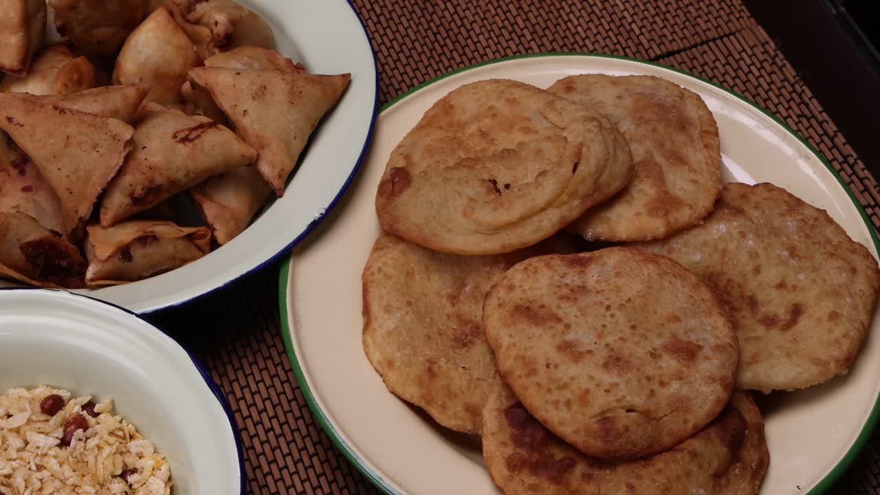 孟加拉风味小吃，各种馅煎饼chitoi bhapa nakshi pakkon pitha singara samosa dal aloo puri炸扁米饭，混合在搪瓷锡金属板上，背景质朴视频下载