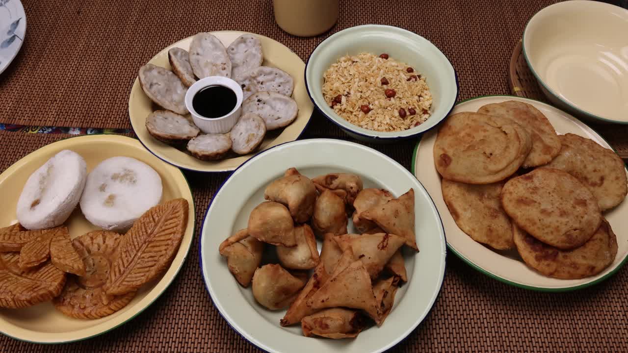 孟加拉风味小吃，各种馅煎饼chitoi bhapa nakshi pakkon pitha singara samosa dal aloo puri炸扁米饭，混合在搪瓷锡金属板上，背景质朴视频素材