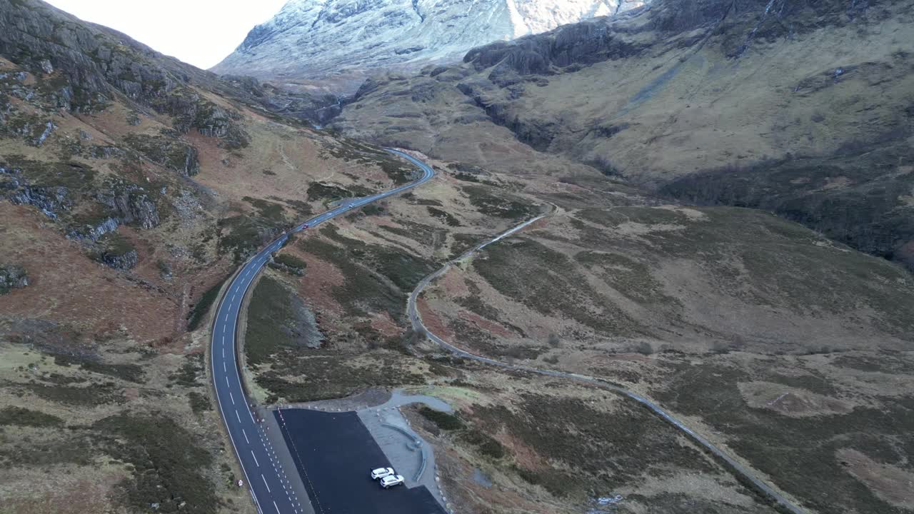 蜿蜒的道路在格伦科与雪山在远处，多云的天气，鸟瞰图视频素材