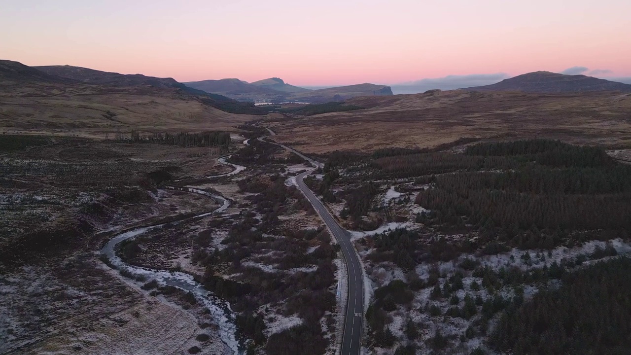 弯弯曲曲的小路穿过崎岖的风景，黄昏时，白雪覆盖，天空苍茫视频素材