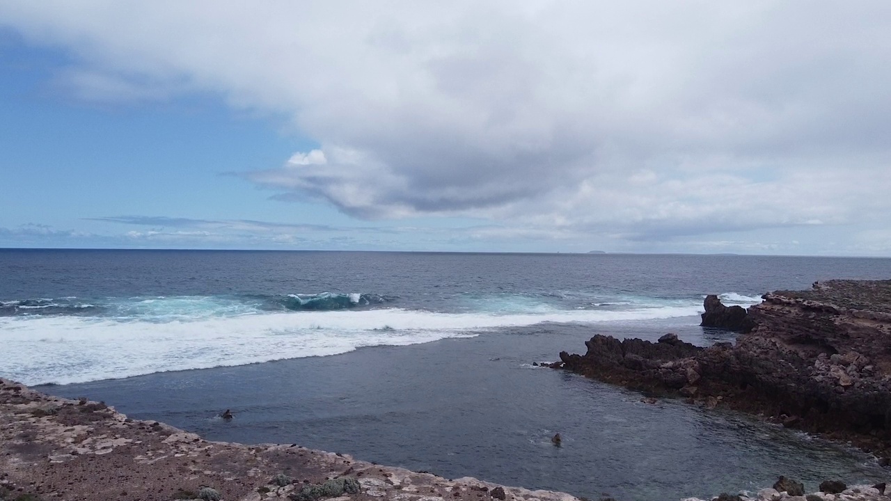 波涛汹涌的海岸线，层层叠叠的岩石架，以及通向宁静海湾的悬崖。视频素材