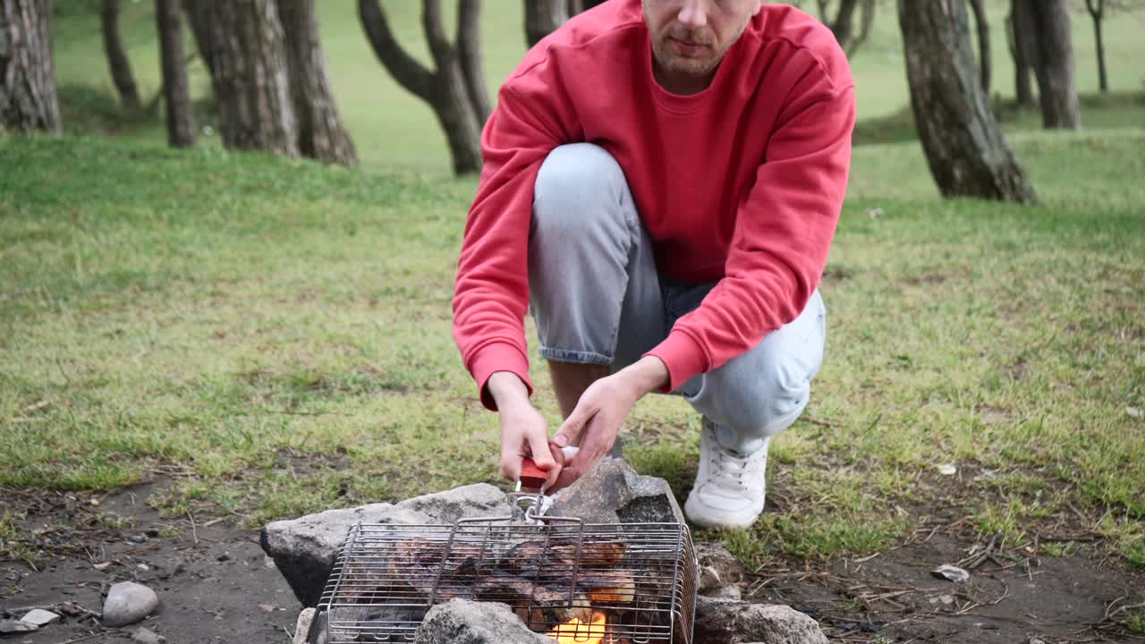 穿红毛衣的男人在烤架上烤肉，他的狗在等晚饭视频素材