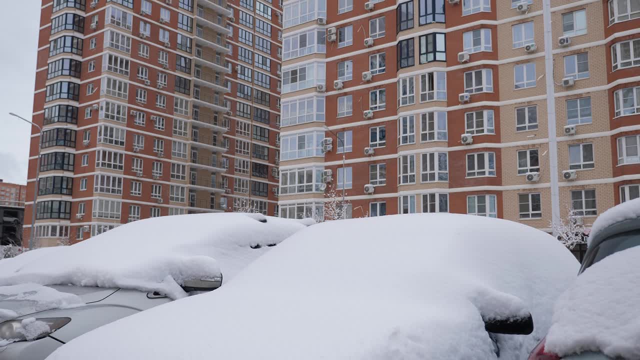 道路和汽车被积雪覆盖在多层建筑的院子里。视频素材