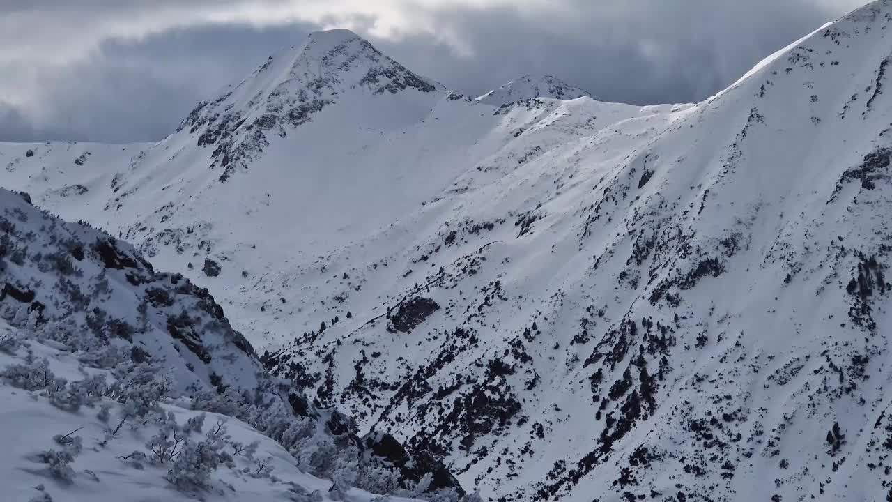 冬天多岩石的山峰上覆盖着毛茸茸的雪，雪暴云下，鸟瞰美景视频素材