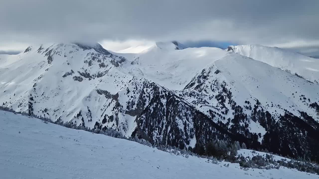 冬天多岩石的山峰上覆盖着毛茸茸的雪，雪暴云下，鸟瞰美景视频素材