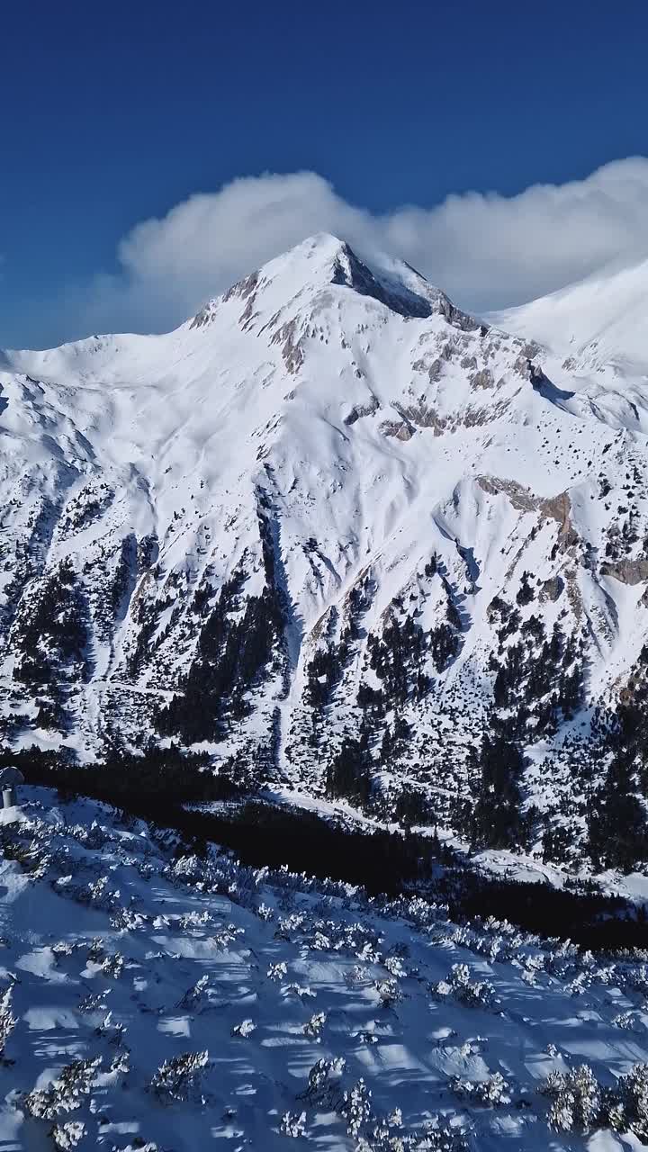 冬天多岩石的山峰上覆盖着毛茸茸的雪，雪暴云下，鸟瞰美景视频素材