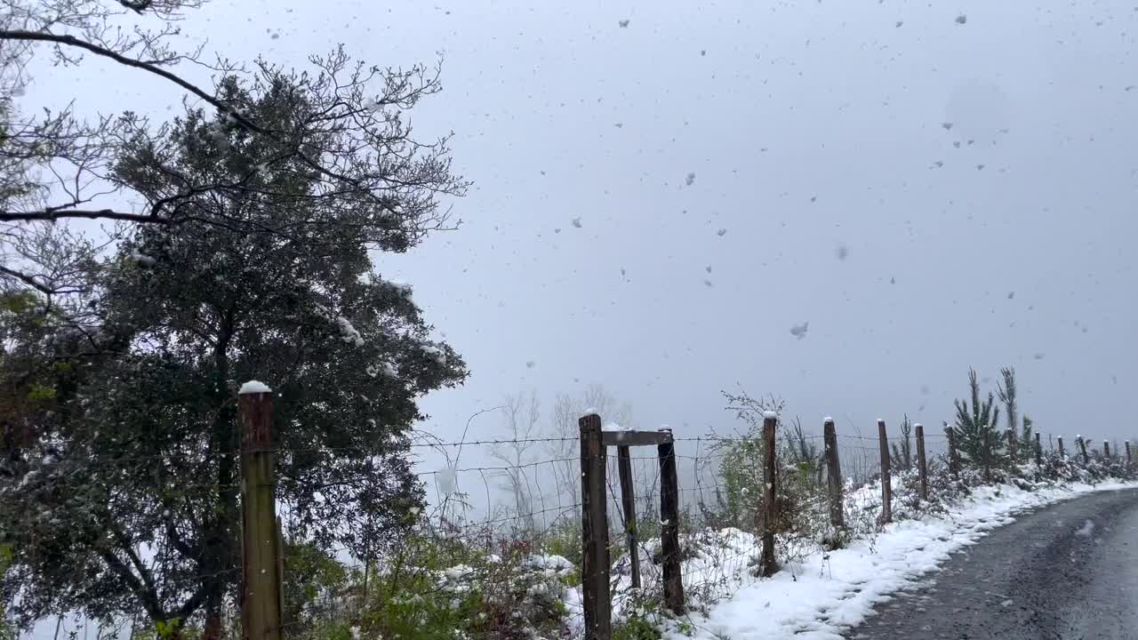 镜头从汽车穿过雪堆沿着山路，冬季风暴视频素材