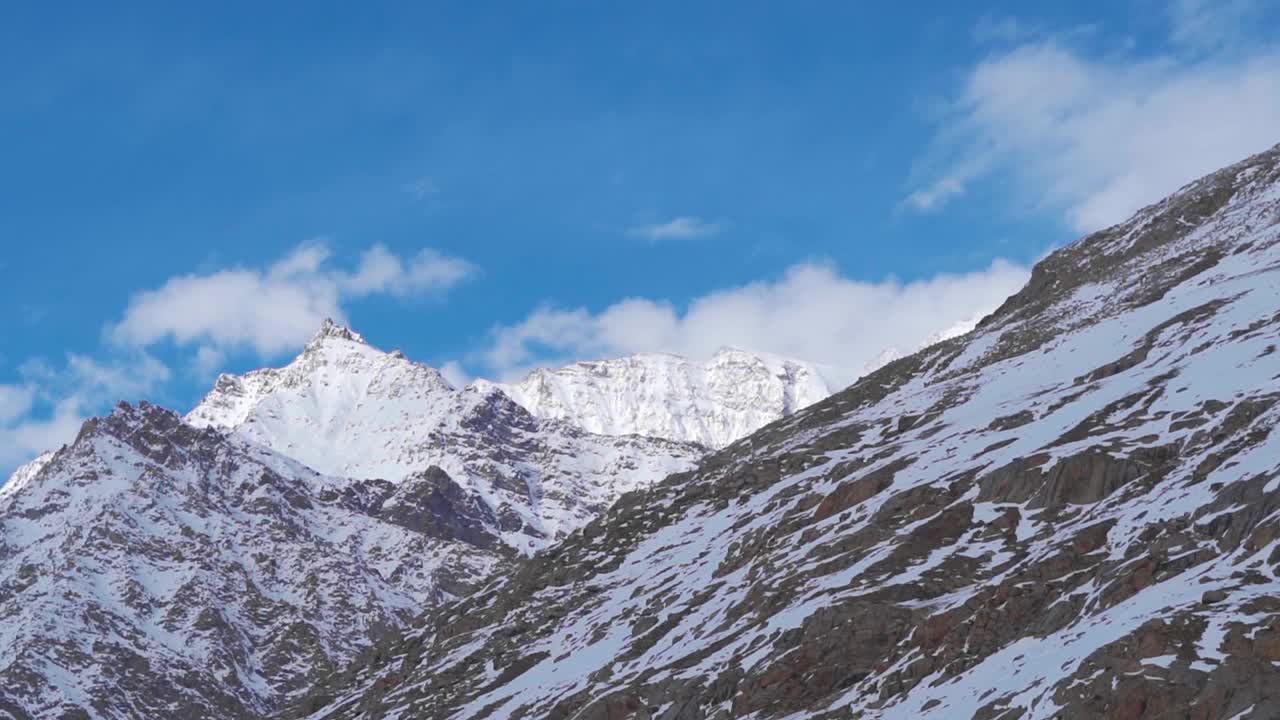 在印度喜马偕尔邦拉胡尔山谷的欣库拉山顶，白天，雪上的云覆盖着喜马拉雅山脉，衬托着冬天的蓝天。冬天，新古拉山口的雪峰。视频素材