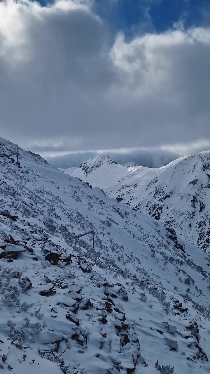 冬天多岩石的山峰上覆盖着毛茸茸的雪，雪暴云下，鸟瞰美景视频素材