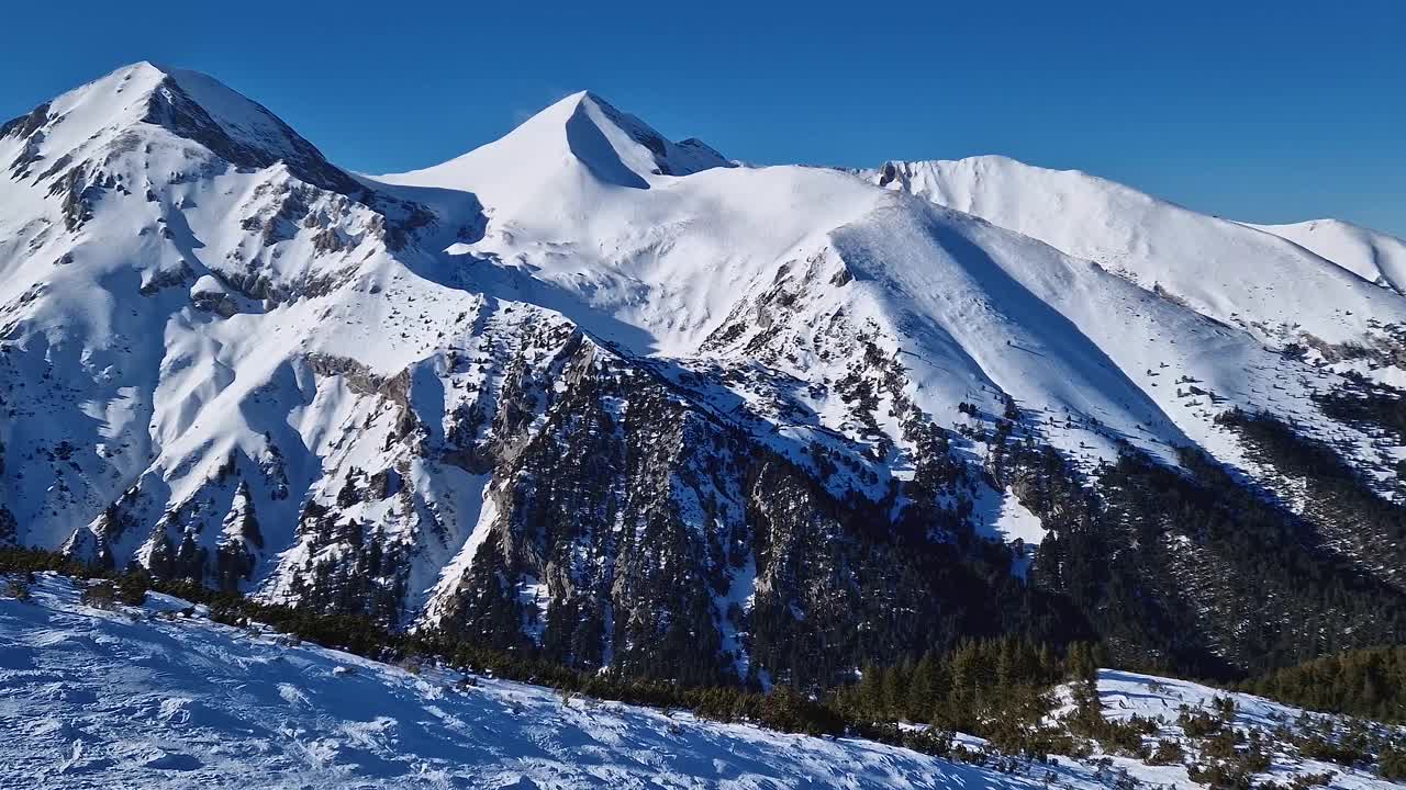 从空中俯瞰皮林山脉，岩石山峰被雪覆盖。保加利亚班斯科滑雪胜地的冬季景色视频素材