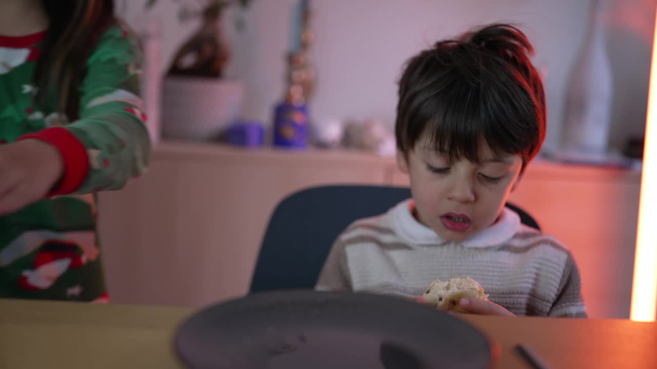 一个小男孩坐在桌边吃着面包。吃了一口碳水化合物食物的孩子视频素材