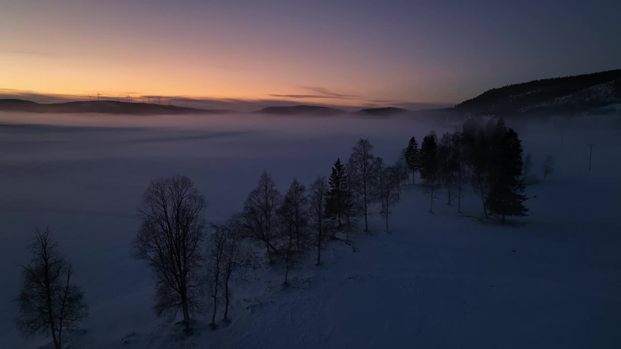 黄昏时的雪景，雾气笼罩着田野，五彩缤纷的天空笼罩在瑞典的松兹瓦尔附近视频素材