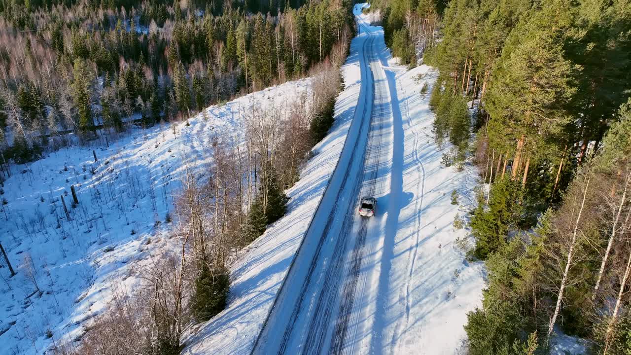 汽车行驶在瑞典Skorped松林中的雪道上，鸟瞰图，阴影笼罩着整个景观视频素材