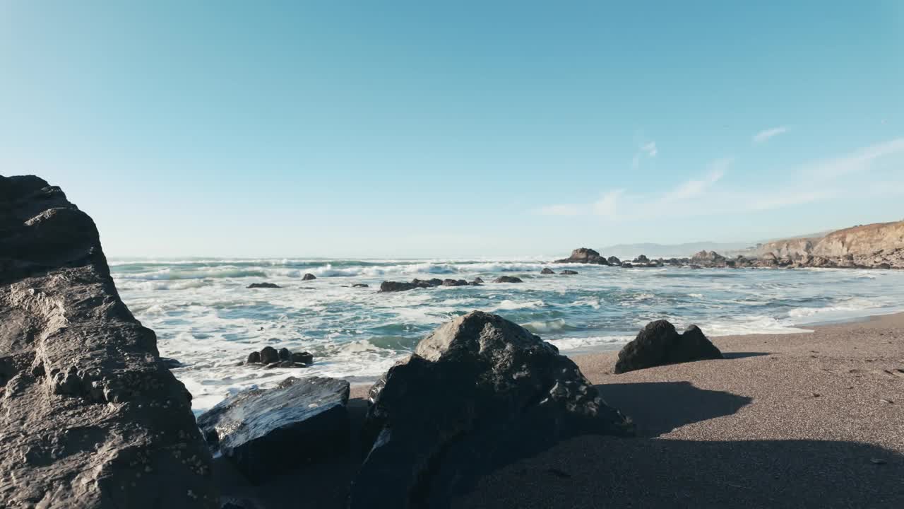 美丽的阳光明媚的一天，蔚蓝的天空，岩石海岸，平静的海浪视频素材