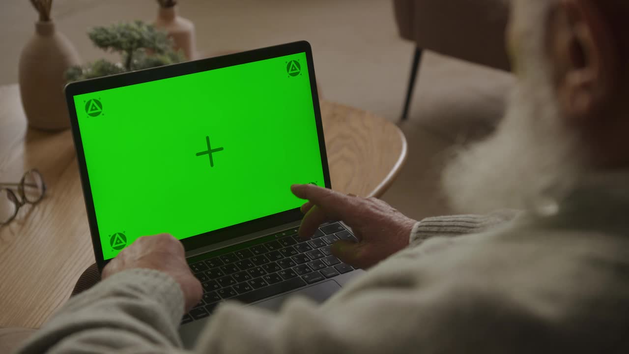 老人在绿屏笔记本电脑上打字视频素材