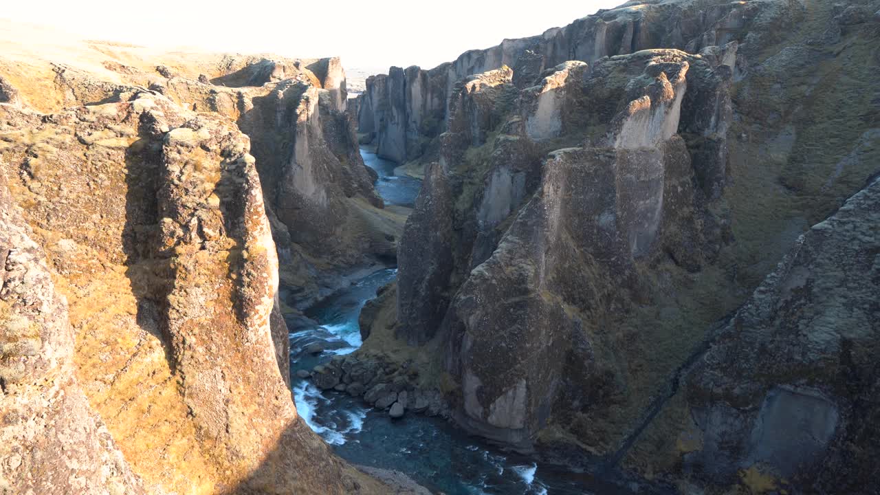 这是一个崎岖的冰岛峡谷，一条河流流经苔藓覆盖的悬崖视频素材