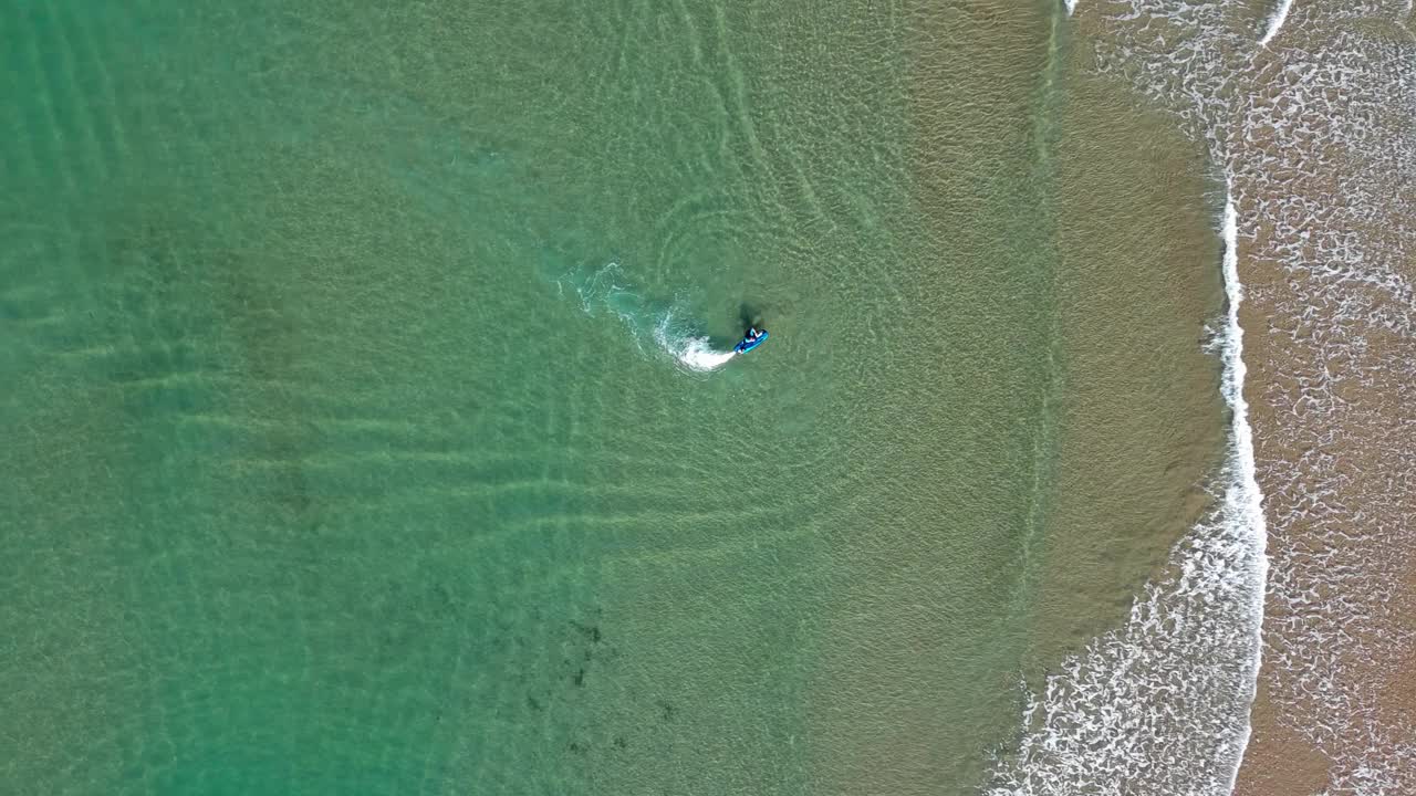 滑板冲浪者在清澈的水域附近的港口吉内斯塔，巴塞罗那，海浪拍打海岸，鸟瞰图视频素材