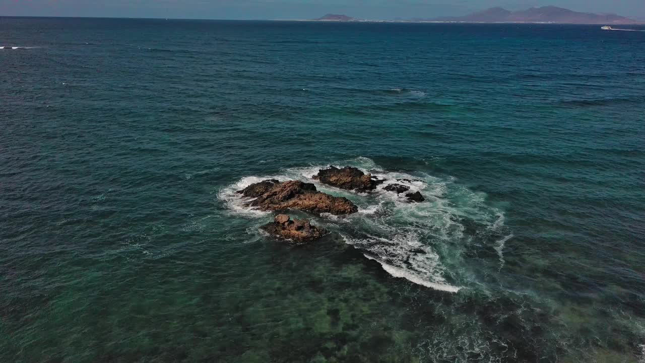 晴朗的一天，鸟瞰图，海浪拍打着加那利群岛corralejo海岸的岩石视频素材